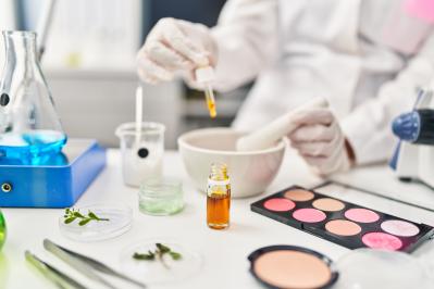 Young hispanic woman scientist making makeup working at laboratory