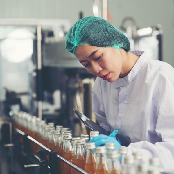 woman looks at bottles on a manufacturing line 