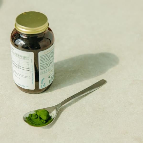 spoon with green powder sitting next to a glass jar