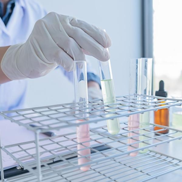 person wearing gloves places test tube in rack