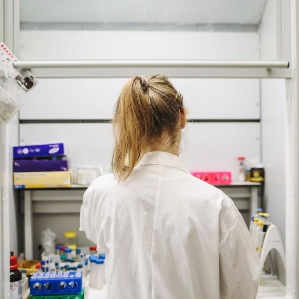 woman in lab coat stands in front of testing instruments